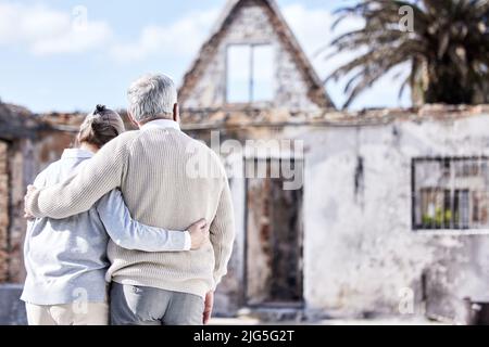 Rupture de cœur brute. Prise de vue d'un couple senior se réconfortant après avoir perdu sa maison à un incendie. Banque D'Images