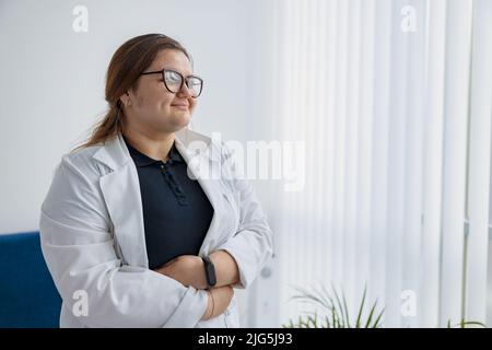 Portrait d'une infirmière en uniforme debout dans le hall de la clinique de médecine et regardant loin Banque D'Images