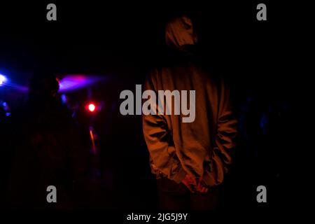 Gars à la discothèque la nuit. Guy se tient avec son dos au concert. Homme à la lumière de la musique légère. Homme en club. Banque D'Images