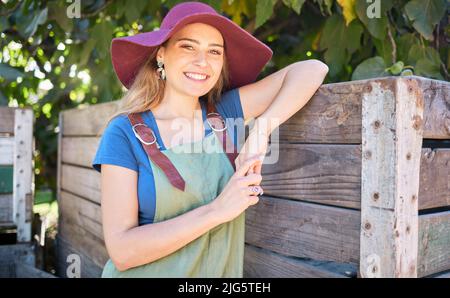 Portrait d'une femme heureuse dans une ferme. Jeune agriculteur sur un verger biologique et durable par une journée ensoleillée. Femme souriant sur des terres agricoles paisibles, penchée sur un Banque D'Images