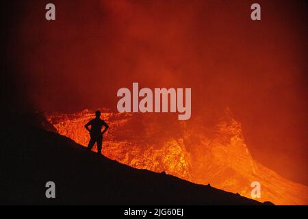 Un explorateur pose près du bord du cratère alors qu'il regarde dans l'évent de Murum, sur l'île d'Ambrym à Vanuatu, au cours d'une expédition pour cartographier le cratère. Banque D'Images