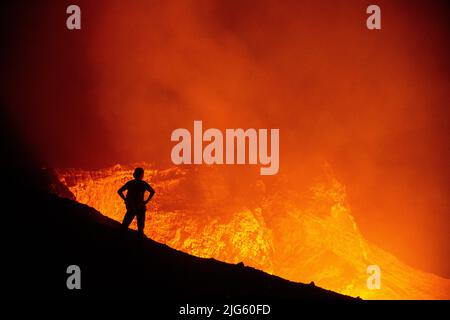 Un explorateur pose près du bord du cratère alors qu'il regarde dans l'évent de Murum, sur l'île d'Ambrym à Vanuatu, au cours d'une expédition pour cartographier le cratère. Banque D'Images