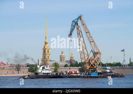 SAINT-PÉTERSBOURG, RUSSIE - 08 JUIN 2022 : grue flottante avec remorqueurs sur toile de fond de la cathédrale Pierre-et-Paul Banque D'Images