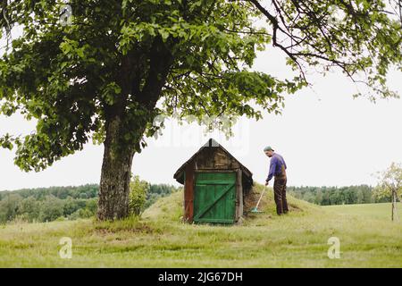 Homme travaillant dans le jardin avec râteau dans une journée ensoleillée. Agriculteur travaillant dans l'arrière-cour Banque D'Images