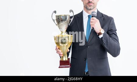 homme mûr et gai en costume tient la tasse de champion et le microphone isolés sur fond blanc Banque D'Images