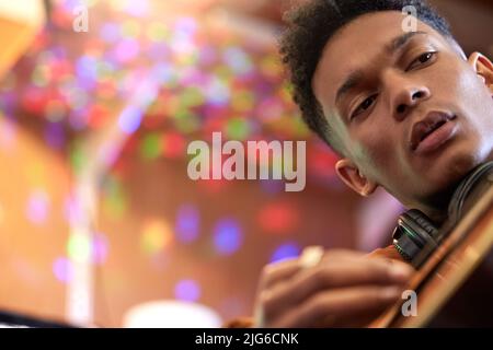 Chaque corde a son propre son unique. Plan court d'un beau jeune musicien masculin jouant sa guitare à la maison. Banque D'Images