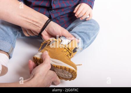 Une mère met des chaussures sur les pieds du petit fils Banque D'Images