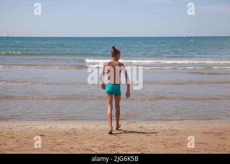 Un adolescent entre dans la mer, vue de l'arrière. Jeune garçon, vue de l'arrière, regarde la mer Méditerranée. Concept de voyage vacances d'été Banque D'Images