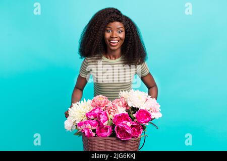 Portrait de gaie charmante petite fille conduire vélo sourire en dents de souris fleurs fraîches panier isolé sur fond bleu-vert couleur Banque D'Images