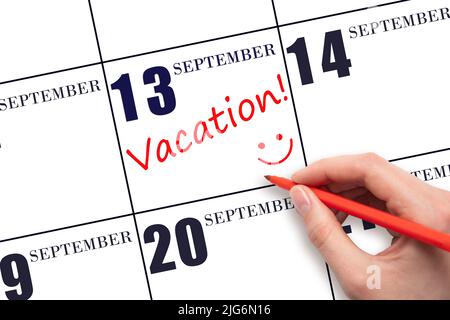 13th jour de septembre. Une main écrivant un TEXTE DE VACANCES et dessinant un visage souriant sur une date de calendrier 13 septembre . Concept de planification des vacances. Automne m Banque D'Images