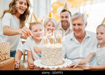 Plus il y a de bougies, plus le souhait est grand. Photo d'une famille heureuse célébrant un anniversaire à la maison. Banque D'Images