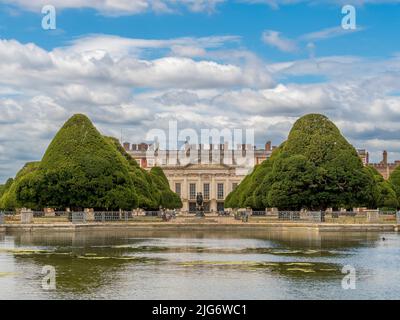 Face est du palais de Hampton court encadré par le jardin de la grande fontaine, les arbres sont plantés de longues eaux au premier plan. Londres. ROYAUME-UNI. Banque D'Images