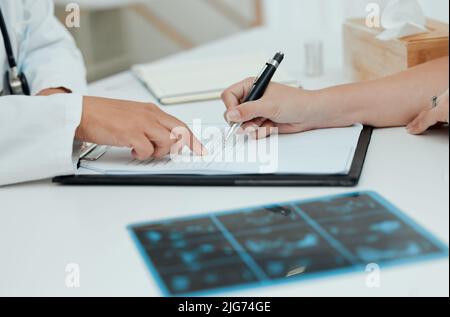 Passons cette liste ensemble. Prise de vue d'une femme méconnaissable remplissant des documents administratifs au cours d'une consultation avec un médecin. Banque D'Images