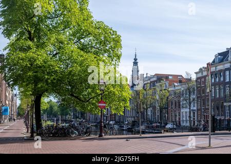 Journée ensoleillée à Amsterdam pays-Bas Hollande. Vélos garés sur un pont de canal au-dessus de l'eau, maisons traditionnelles en brique façade et rues pavées Banque D'Images