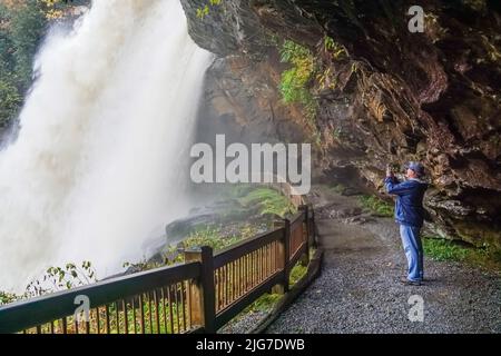 Un randonneur mâle se trouve sur le sentier derrière la chute d'eau de Dry Falls en Caroline du Nord Banque D'Images
