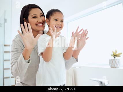 Nous avons couvert chaque doigt. Photo d'une adorable petite fille se lavant les mains pendant que sa mère aide à la maison. Banque D'Images