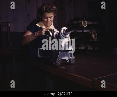 Une jeune femme employée de North American Aviation, Incorporated, travaillant sur le mécanisme du train d'atterrissage d'un avion de chasse P-51, Inglewood, en Californie, le mécanisme ressemble à un petit canon. Banque D'Images