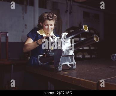 Une jeune femme employée de North American Aviation, Incorporated, travaillant sur le mécanisme du train d'atterrissage d'un avion de chasse P-51, Inglewood, en Californie, le mécanisme ressemble à un petit canon. Banque D'Images