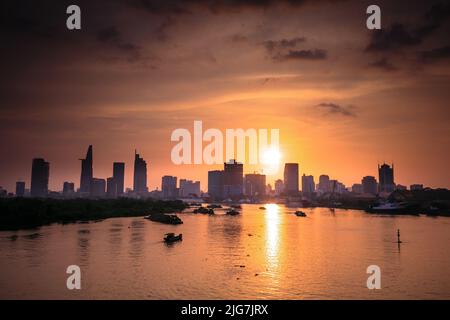 Vue panoramique d'Ho Chi Minh sur le fleuve Saigon. Un éclairage spectaculaire un coucher de soleil spectaculaire est mis en évidence par un canoë surfant sur l'eau à un rat plus rapide Banque D'Images