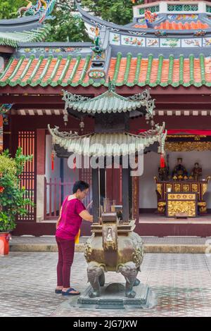 Une femme allume un bâton dans les cours du Temple de Thian Hock Keng, ou Temple de bonheur céleste, Singapour. Le temple date de 1839 A. Banque D'Images