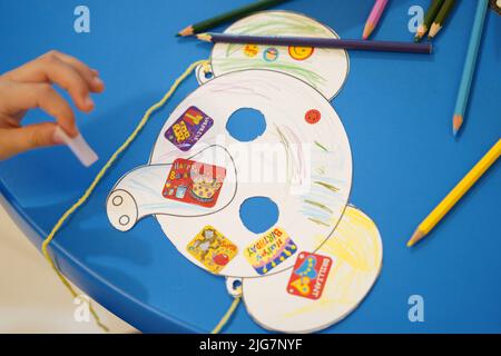 Un petit enfant colorant un masque en papier animal dans la salle de classe. Masque en papier éléphant art et artisanat. Banque D'Images