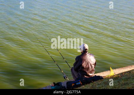 Un homme pêche avec deux cannes à pêche au bord du lac Banque D'Images