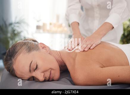 Et maintenant son temps moi. Photo d'une femme adulte bénéficiant d'un massage relaxant du dos au spa. Banque D'Images