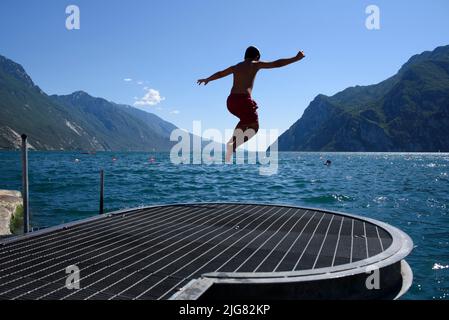 8 juillet 2022, Riva del Garda, Varsovie, Italie: Un garçon saute dans le lac de Garde pendant une après-midi chaude sur 8 juillet 2022 à Riva del Garda, Italie. (Image de crédit : © Aleksander Kalka/ZUMA Press Wire) Banque D'Images