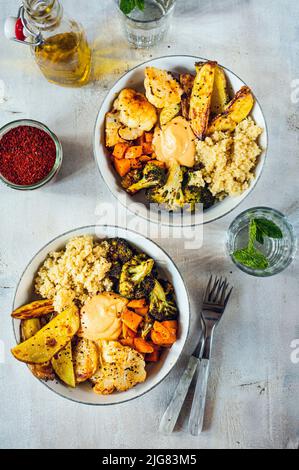 Pommes de terre rôties, patate douce, brocoli avec riz brun et houmous, végétalien Banque D'Images