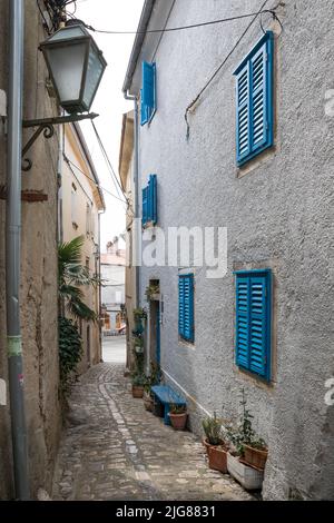 Ruelle étroite et bâtiment avec des volets bleus dans la vieille ville, la ville de Krk, l'île de Krk, la baie de Kvarner, comté de Kotar Primorje-Gorski, Croatie, Europe Banque D'Images