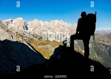 Italie, Vénétie, Belluno, Canale d'Agordo, randonneur en silhouette au lever du soleil avec la crête de montagne de Pale di San Martino en arrière-plan Banque D'Images