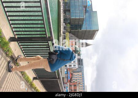 Jeune homme debout sur une balustrade de pont, vue sur le Liffey, Dublin, Irlande Banque D'Images