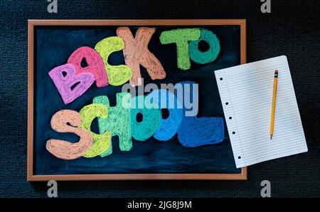 Retour à l'école lettres signe écrit sur un tableau noir, papier et crayon Banque D'Images