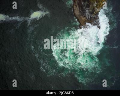 Prise de vue aérienne. Eaux turquoise de l'océan, vagues de mousse blanche s'écrasant contre la rive rocheuse. Abstraction. La beauté et la majesté de la nature Banque D'Images