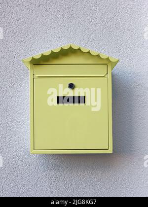 Boîte aux lettres jaune accrochée au mur blanc Banque D'Images