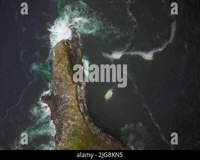 Tir à partir d'un drone. Une petite île longue dans l'océan, lavée de tous les côtés par les vagues. Il n'y a personne dans la photo. Scènes calmes. Beauté de la nature. Banque D'Images