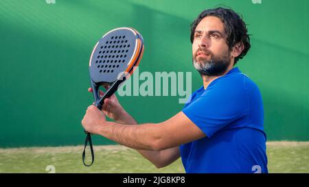 Homme qui joue au padel tennis avec de l'espace pour le texte. Sportif de joueur caucasien. Moniteur de padel tenant une raquette noire avec espace de copie. Sports de Raquettes gam Banque D'Images