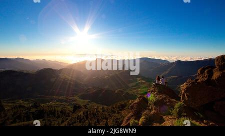 Espagne, Iles Canaries, Grande Canarie, massif Central, Roque Nublo, Coucher de soleil, vue sur le massif Central vers l'ouest, Teide, couple assis de derrière, ciel bleu, soleil comme étoile Banque D'Images