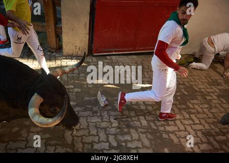 Un coureur conduit un taureau à la arène de Pampelune, appartenant au ranch de Fuente Ymbro pendant la deuxième course des taureaux de la partie des festivités de San Fermín 2022. Banque D'Images