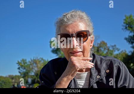 Femme âgée sur des lunettes de soleil souriant Banque D'Images