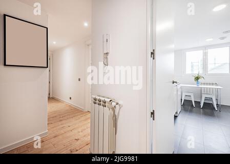 Couloir d'une maison avec plusieurs portes et accès à différentes chambres, toutes en parquet blanc et une table à manger blanche Banque D'Images