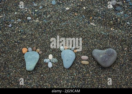 Concept d'amour. Marches de l'homme, de la femme et du coeur en pierres sur la plage de sable. Banque D'Images