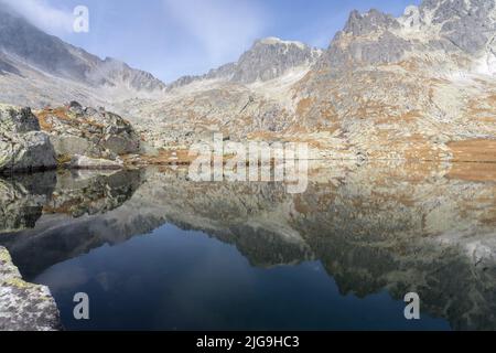 Lac alpin encore reflétant les montagnes rocheuses avec des couleurs d'automne l'entourant, Slovaquie, Europe Banque D'Images