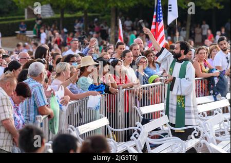 Un prêtre bénit les articles religieux des fidèles après la Messe du soir à Medjugorje. Banque D'Images