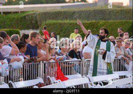 Un prêtre bénit les articles religieux des fidèles après la Messe du soir à Medjugorje. Banque D'Images