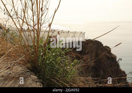 Serre de plastique blanc avec structure visible au bord de la mer et des montagnes Banque D'Images