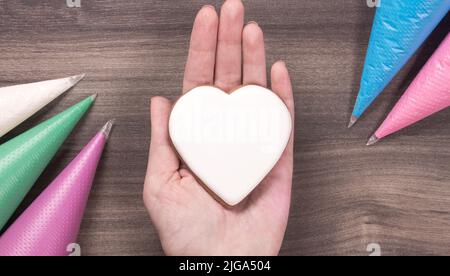 Cookie en forme de coeur blanc pour la fête des mères, la fête des femmes ou la fête de la Saint-Valentin sur fond de bois.Copier l'espace. Banque D'Images