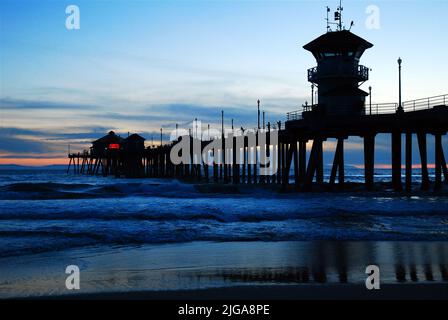 Les vagues se roulent sur la rive à la jetée de Huntington Beach pendant le coucher du soleil dans le centre de villégiature du comté d'Orange en Californie Banque D'Images