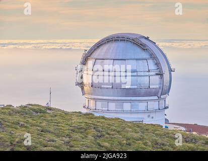 Gros plan d'un observatoire astronomique avec ciel clair et espace de copie. Télescope entouré de verdure et situé sur une île au bord d'une falaise Banque D'Images
