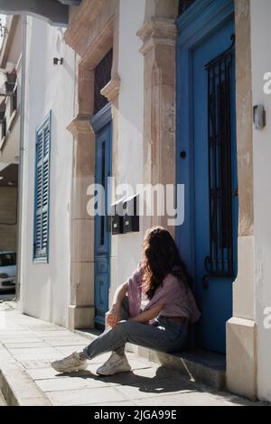 Femme est assise près de beau bâtiment avec des portes bleues à Larnaca, Chypre Banque D'Images